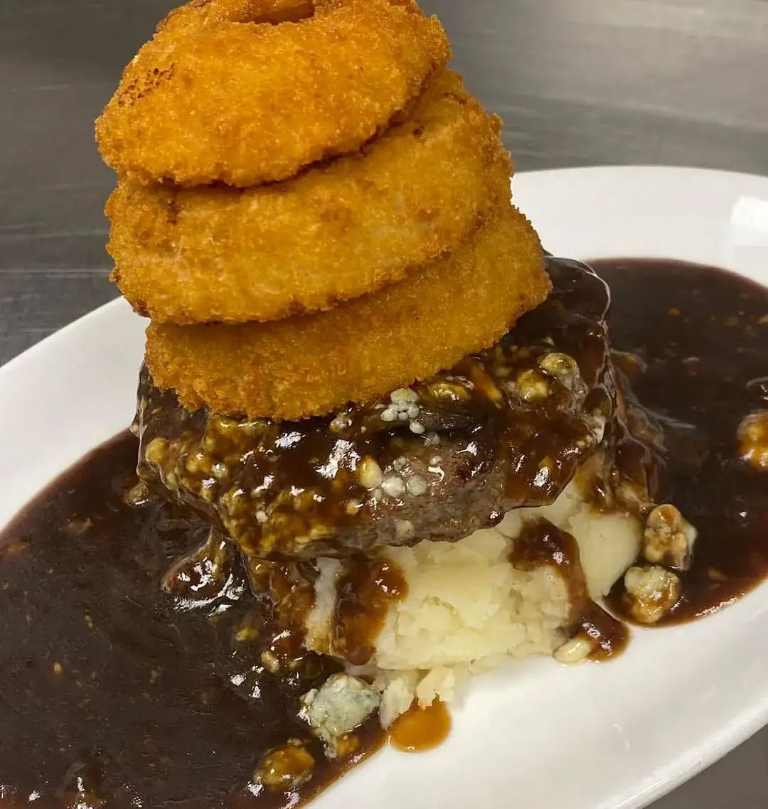 Bleu cheese burger topped with a stack of onion rings over mashed potatoes and gravy at McNamaras Pub in Crystal City Arlington VA